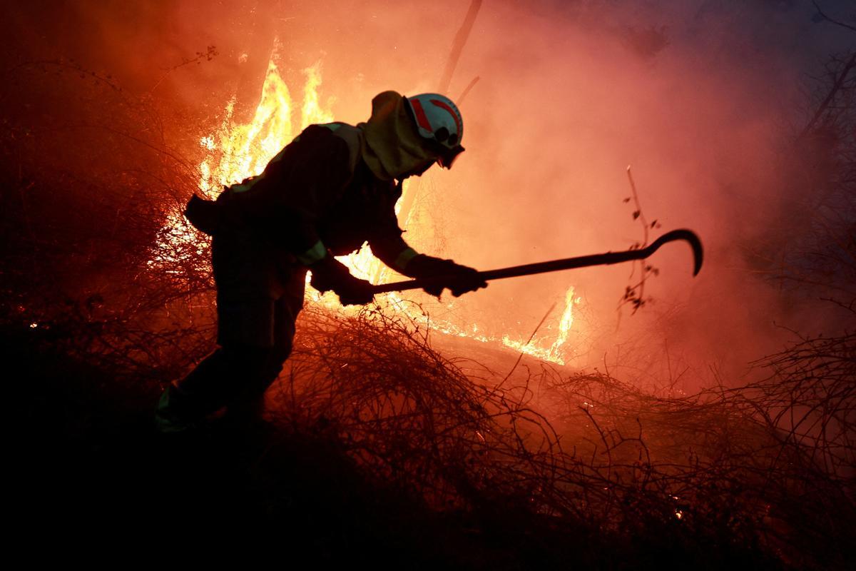 Un bombero gallego hace frente a las llamas en un bosque durante un brote de incendios forestales, en Piedrafita, Asturias