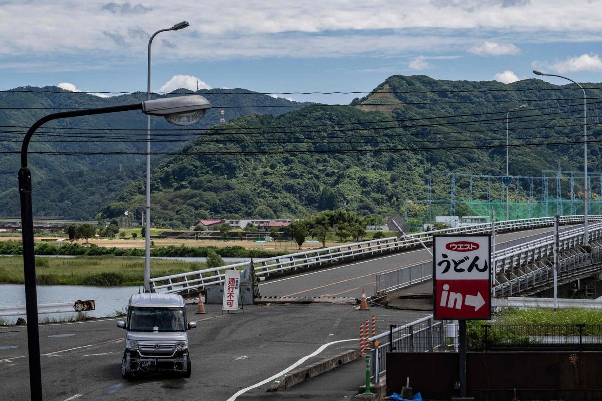 Un vehículo varado se encuentra frente a un puente dañado por el terremoto en Yatsushiro, prefectura de Kumamoto, el 29 de julio de 2026, después de que un terremoto sacudió el suroeste de Japón el día anterior. (Foto de Yuichi YAMAZAKI / AFP)