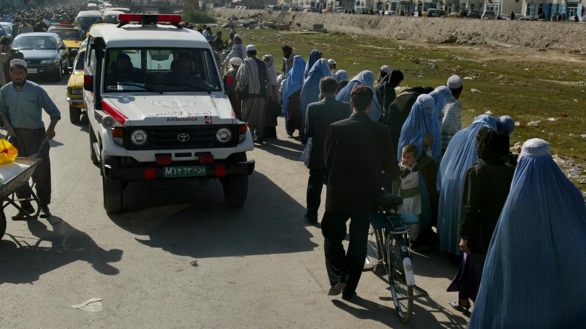 Una ambulancia pasa junto a una fila de mujeres con burka en Kabul.