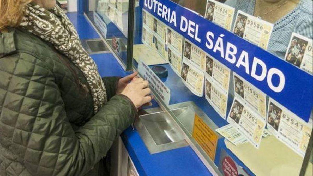 Una mujer compla lotería en una administración.