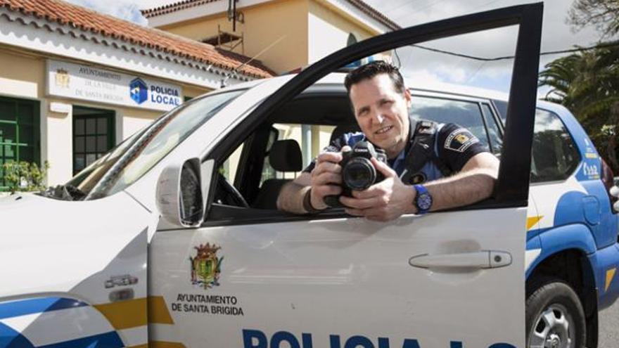 El agente Javier Plaza, con su cámara entre las manos y apoyado en la puerta de un coche patrulla. | quique curbelo
