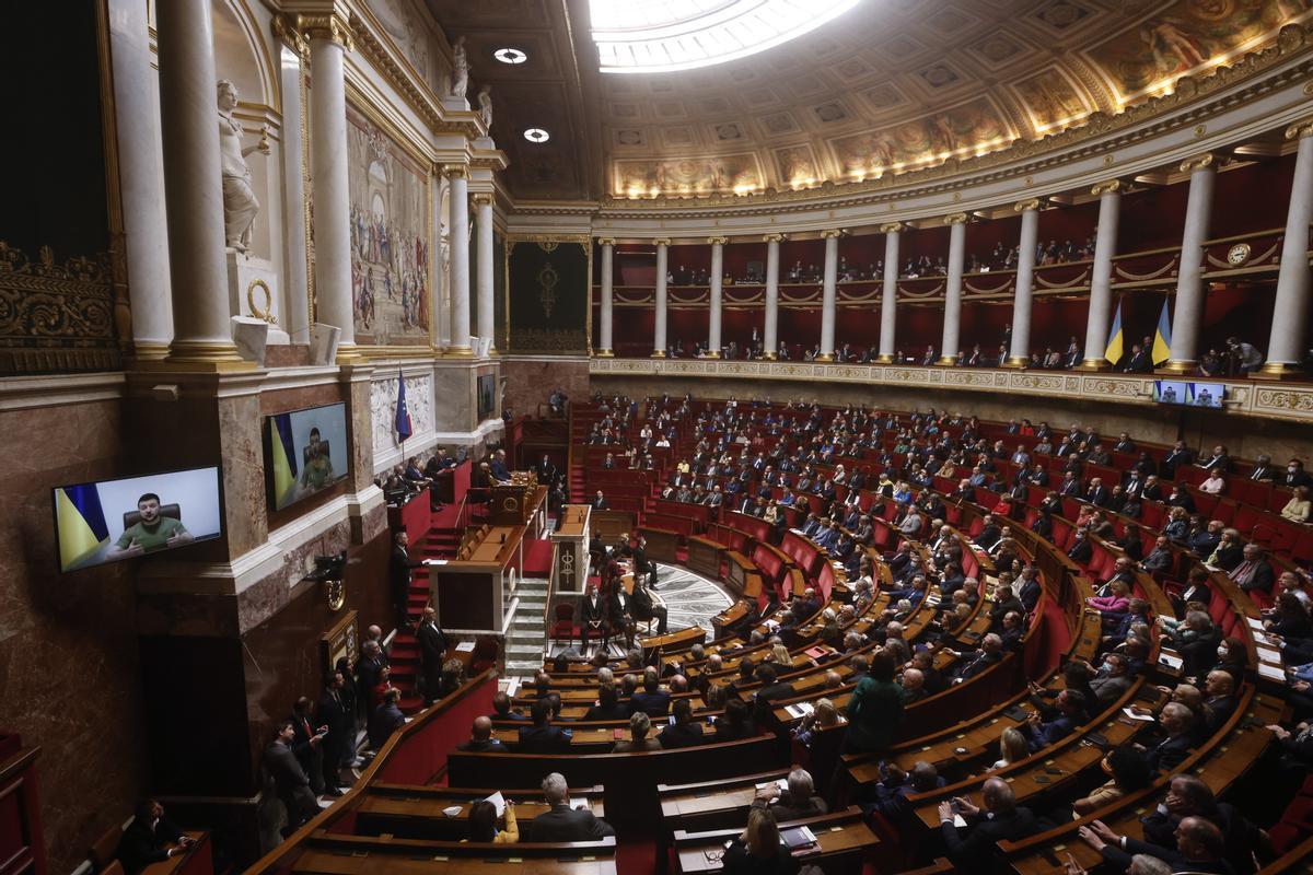 El presidente de Ucrania, Volodymyr Zelensky (en la pantalla), se dirige a los representantes franceses durante una videoconferencia en la Asamblea de la Nación en París, Francia.