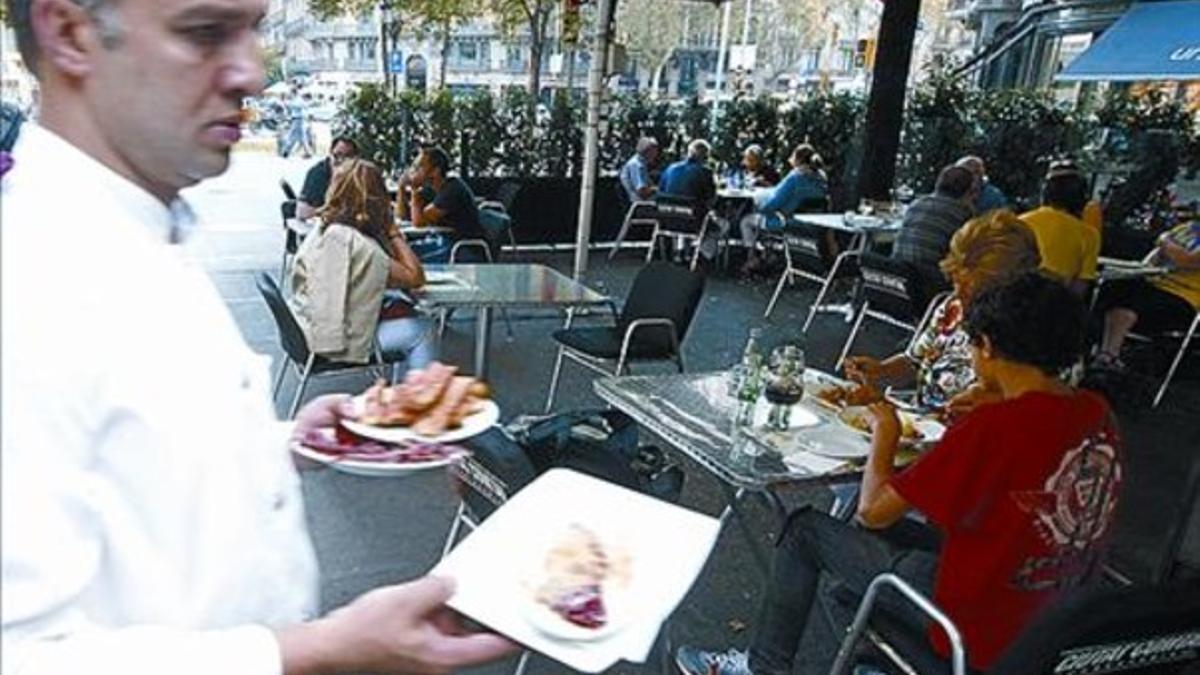 Un camarero atiende una terraza en la Ramba de Catalunya.