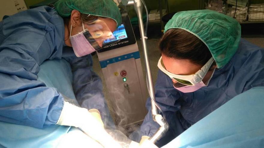 Dos sanitarios utilizando el láser con una paciente.