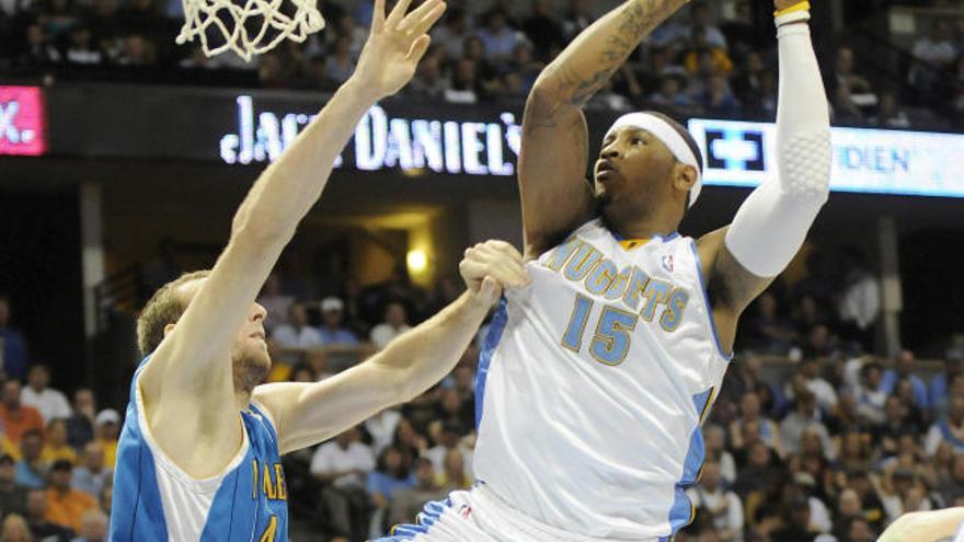 El jugador de los Nuggets de Denver Carmelo Anthony recibe una falta de Ryan Bowen de los Hornets de Nueva Orleans durante el juego de la fase final de la NBA que se disputa en el Pepsi Center de Denver