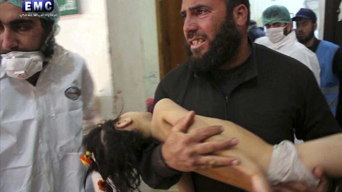 Un hombre lleva en brazos a un niño herido por gas tóxico en Idleb.