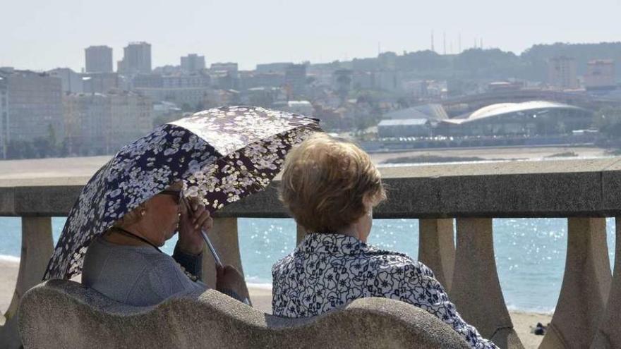 Dos señoras en un banco del paseo marítimo de A Coruña en una jornada de buen tiempo.
