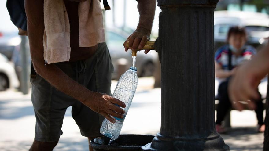 Un hombre llena una botella de agua en una fuente.