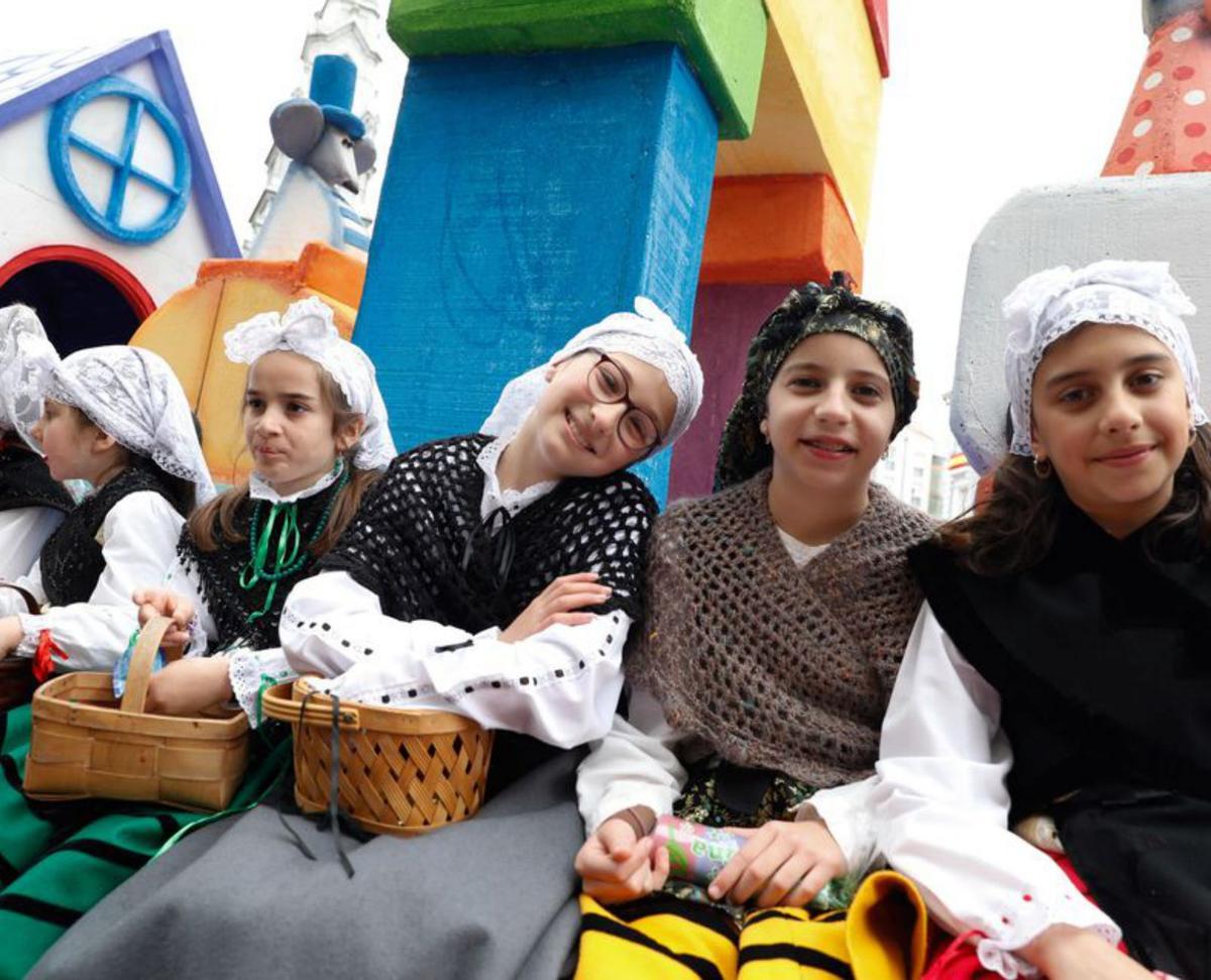 A la izquierda, varias niñas ataviadas con trajes regionales y subidas a una de las carrozas. En el centro, una niña durante el desfile delante de la banda de gaitas de Corvera. A la derecha, el recorrido en la calle José Cueto. | MARA VILLAMUZA