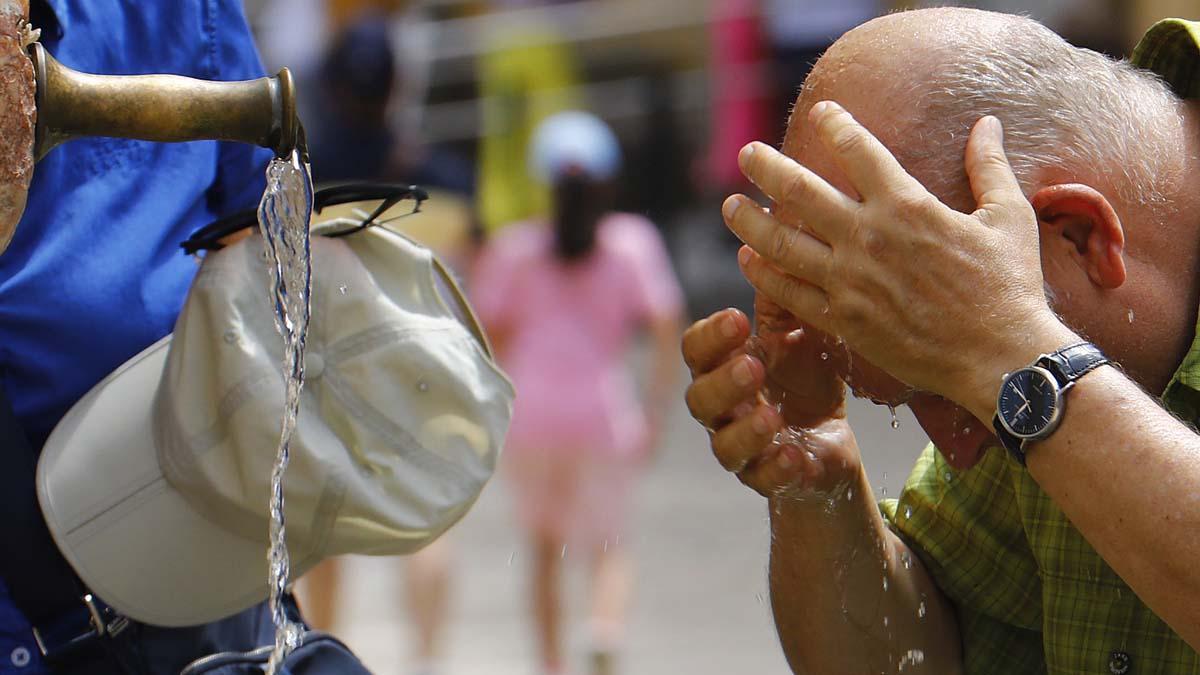 Un turista se refresca en una de las fuentes del Patio de los Naranjos de la Mezquita catedral de Córdoba para aliviar las altas temperaturas.