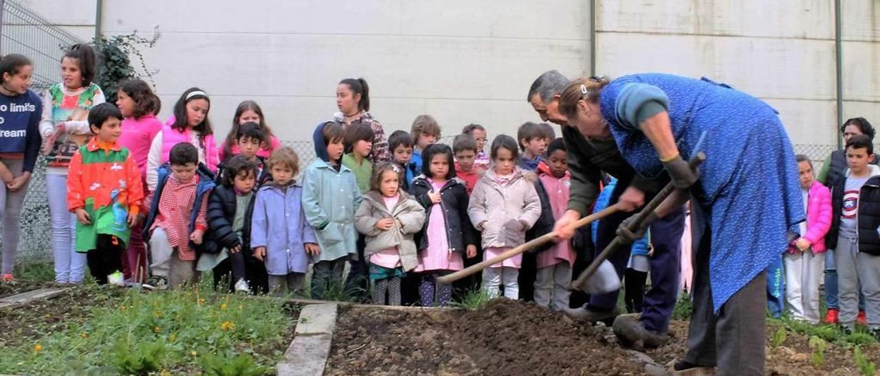 Laurentina del Corro y Jaime Menéndez preparan la tierra ante la mirada de los escolares quirosanos.