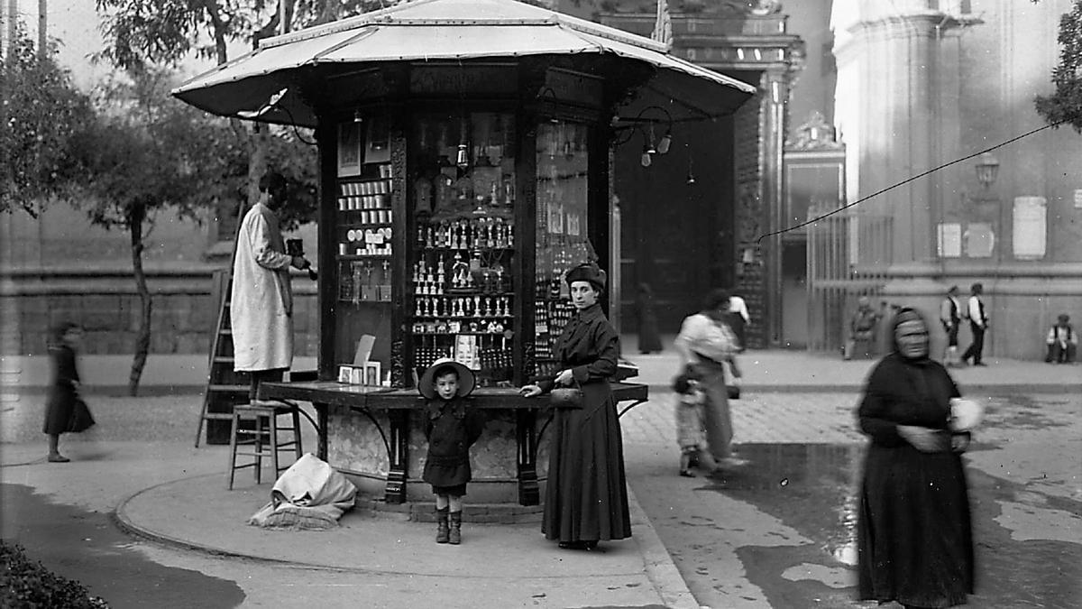 Familiar estampa capturada en la plaza del Pilar junto a uno de los cuatro quioscos que flaqueaban pareados el acceso a la Puerta Baja del templo mariano, confrontando con el inmueble del número 19 y la puerta del Pasaje de la Industria en 1914