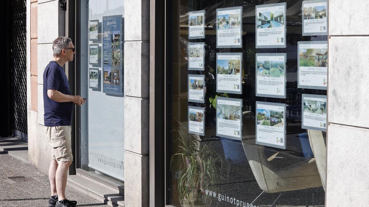 Un home davant l’aparador d’una immobiliària a Girona.