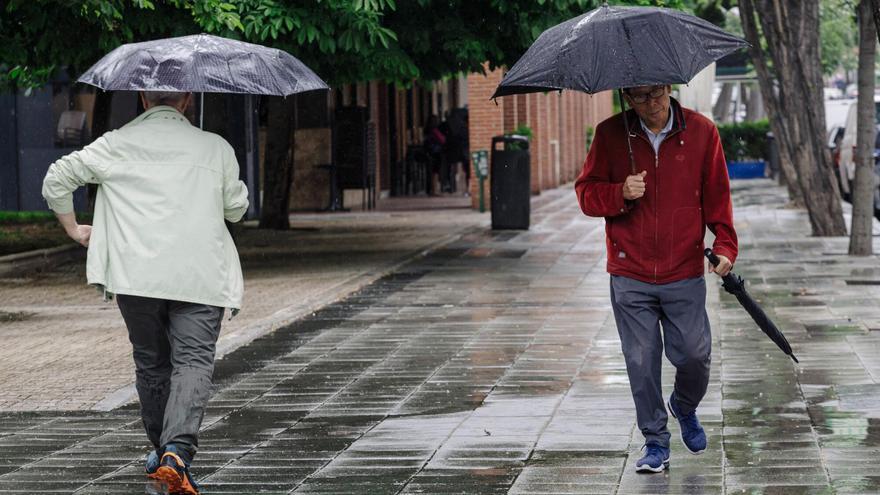 Dos personas pasean bajo la lluvia.