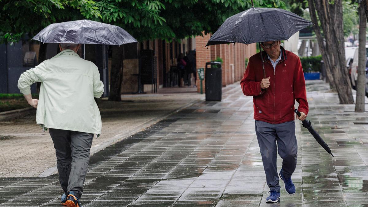 Dos personas pasean bajo la lluvia.