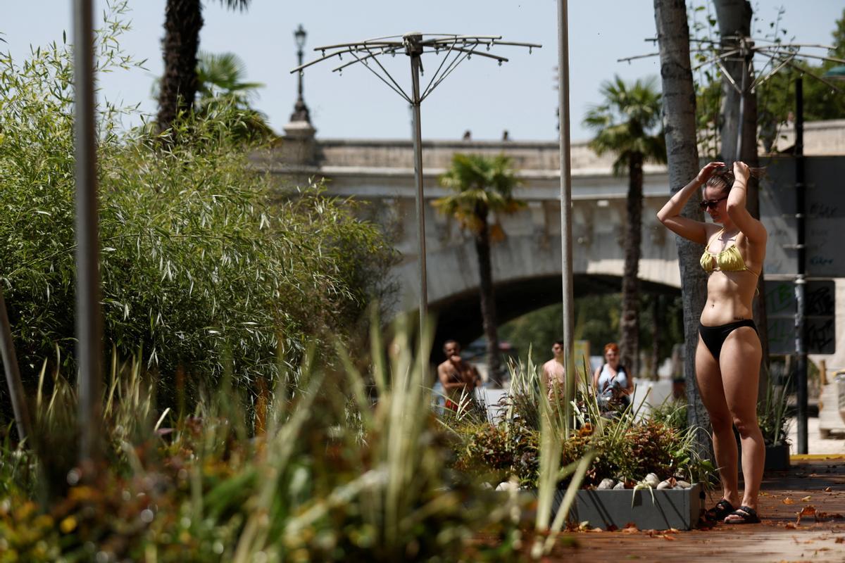 Una mujer se refresca en una máquina de niebla en el evento Paris Plage durante una ola de calor en París.