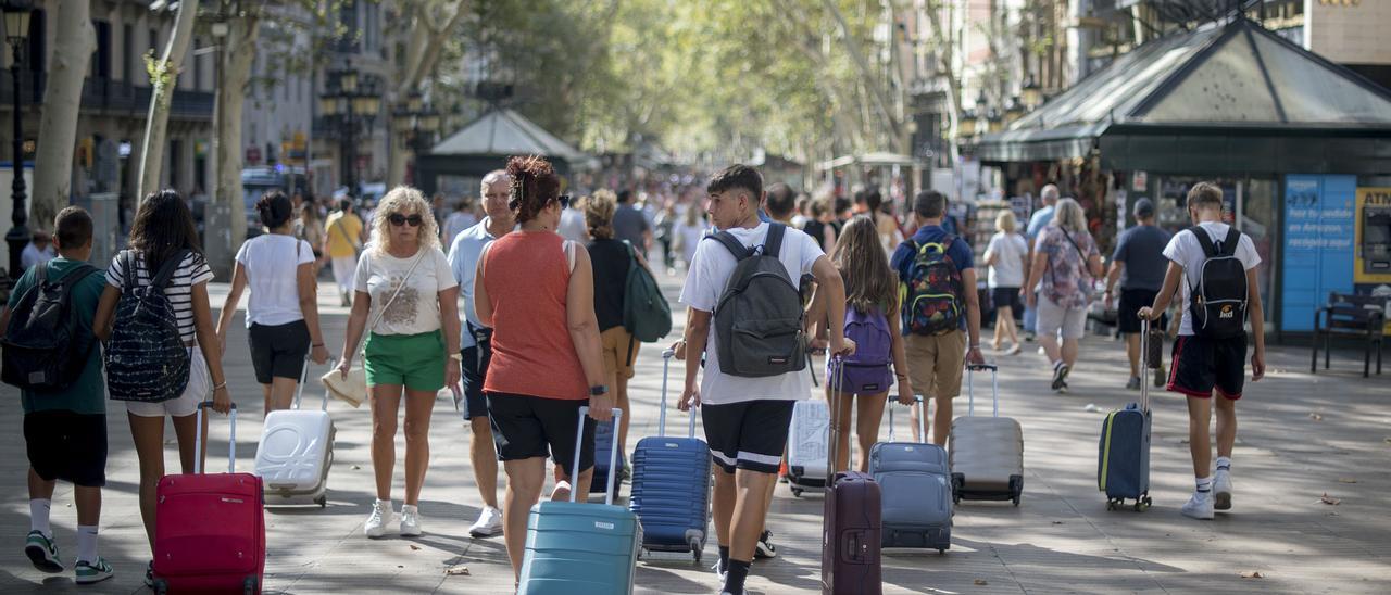 Turistas con sus maletas por las Ramblas