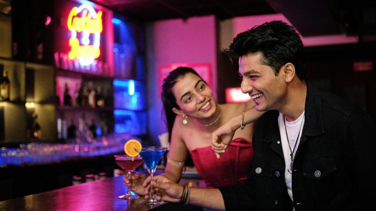 Dos jóvenes toman un cóctel en un bar.