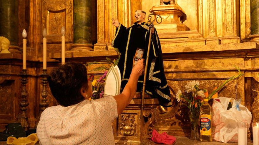 Una devota pasa una estampa por la imagen del santo. |  A. Irago
