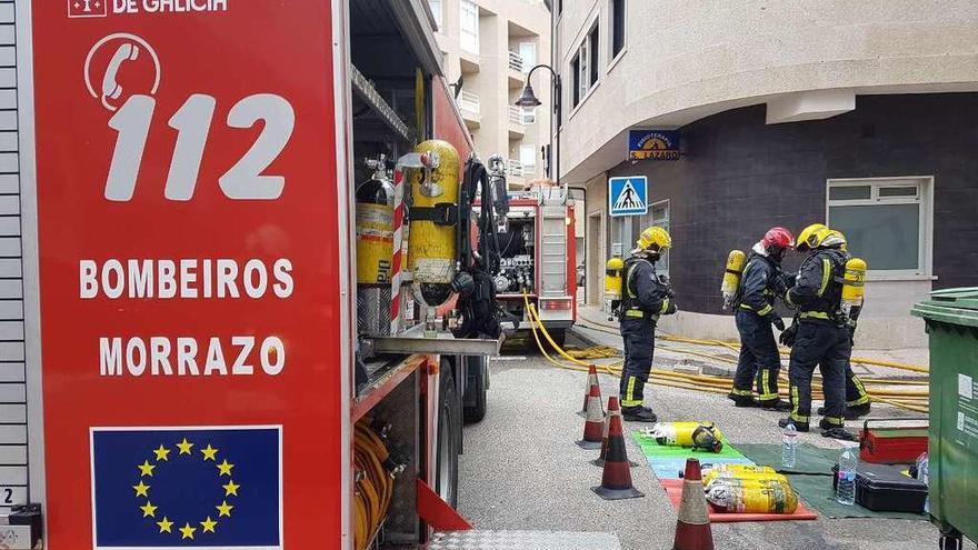 Varios bomberos con bombonas de oxígeno, a las puertas del inmueble afectado por el fuego. // G. Núñez