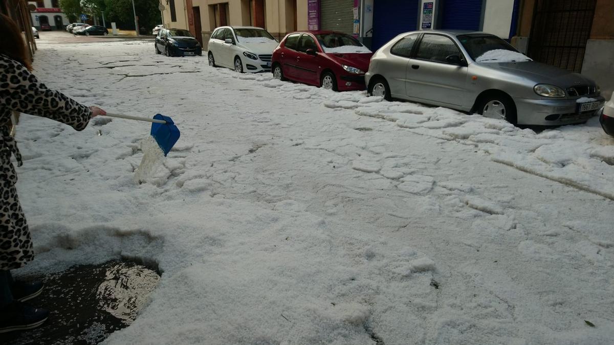 Vecinos de la calle Colon de Nules retirando el granizo