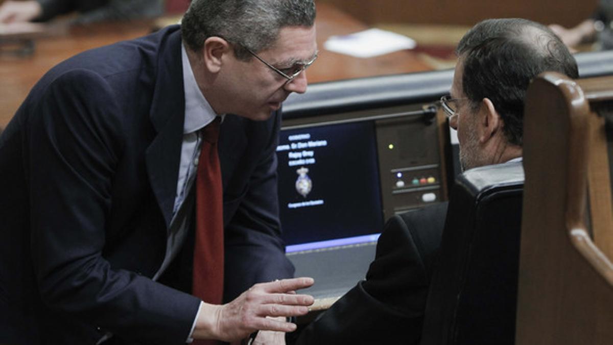 El ministro de Justicia, Alberto Ruiz Gallardón, habla con el presidente del Gobierno, Mariano Rajoy, este jueves, en el Congreso.