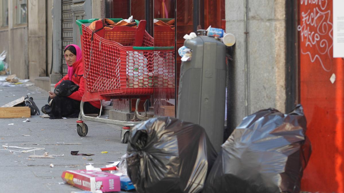 Una mujer sin hogar pide dinero en la calle.