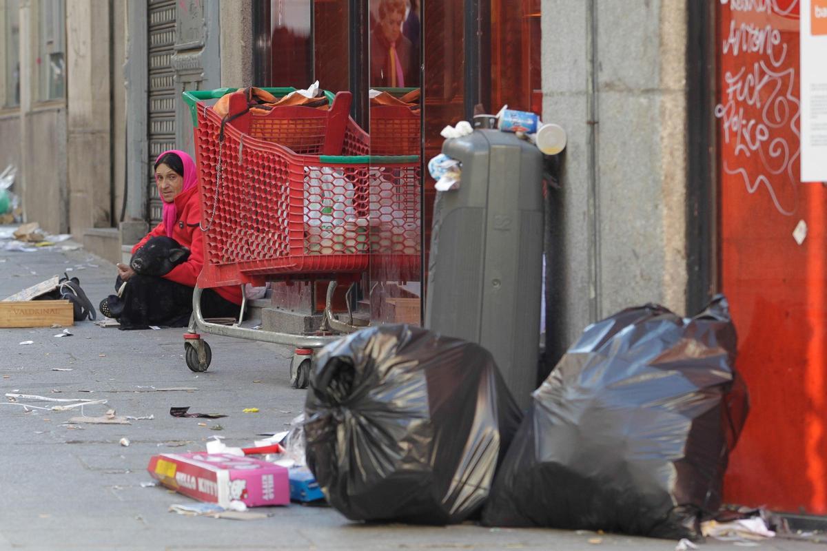 Una mujer sin hogar pide dinero en la calle.