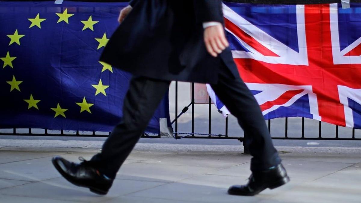 Un hombre camina junto a una bandera de la UE y otra del Reino Unido, en Londres.