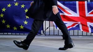 Un hombre camina junto a una bandera de la UE y otra del Reino Unido, en Londres.