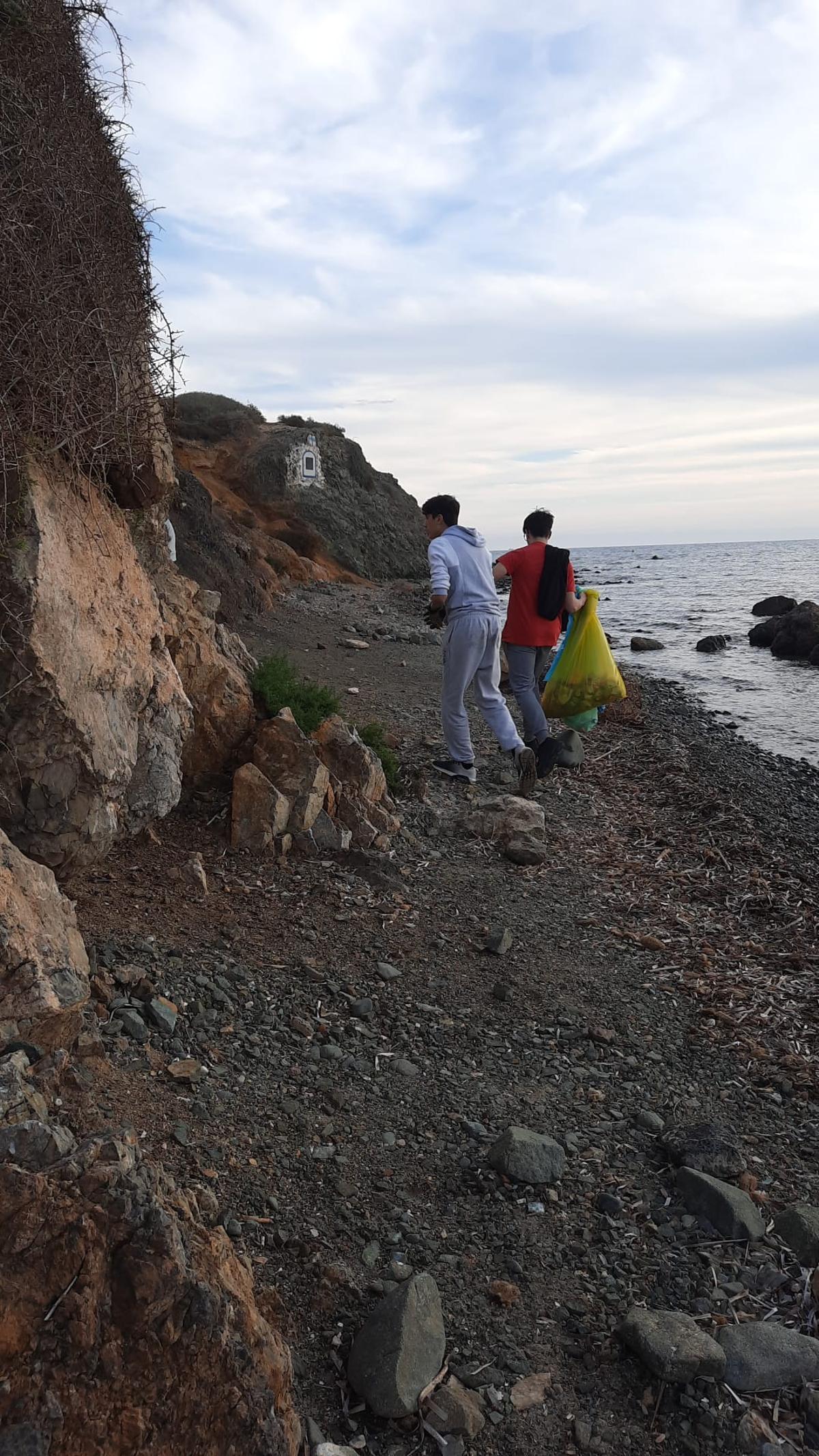 Jóvenes recogiendo residuos con bolsas en la isla de Tabarca