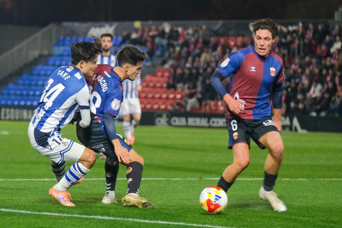 ELDA (ALICANTE), 16/12/2025.- El delantero de la Real Take Kubo (i) pelea un balón con Guillermo Macho (c) y Borja Calvo, ambos del Eldense, durante el partido de dieciseisavos de la Copa del Rey que CD Eldense y Real Sociedad disputan este martes en el estadio Nuevo Pepico Amat, en Elda. EFE/Pablo Miranzo