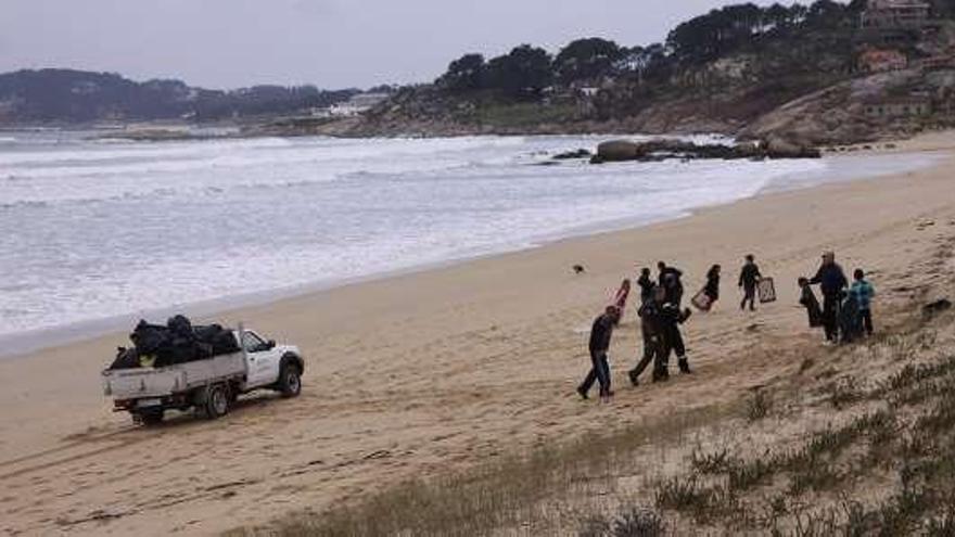 1 - Tres de las voluntarias, en el momento de iniciar el trabajo en la playa., 2 - El concejal de Medio Ambiente, Alfredo Bea, también colaboró en la limpieza., 3 - Los trabajos se realizaron sobre la playa y en el cordón dunar., 4 - Algunos voluntarios, cuando recibieron explicaciones sobre lo que había que hacer., 5 - Entre los participantes también había niños., Los voluntarios tuvieron una furgoneta de apoyo.  //  Muñiz