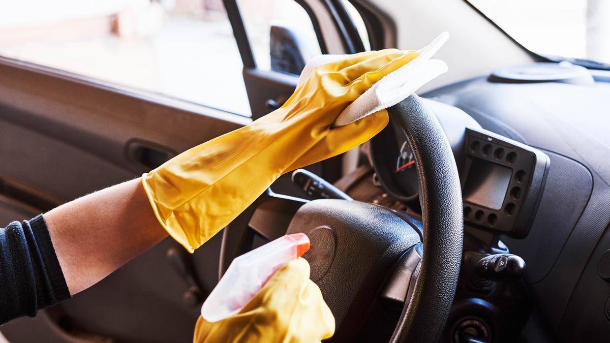 Una persona limpia el volante y el interior del coche