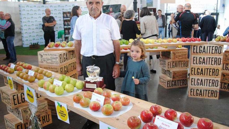 Elías Carneado, con su nieta Ángela, en Villaviciosa, en el expositor de manzana de mesa.