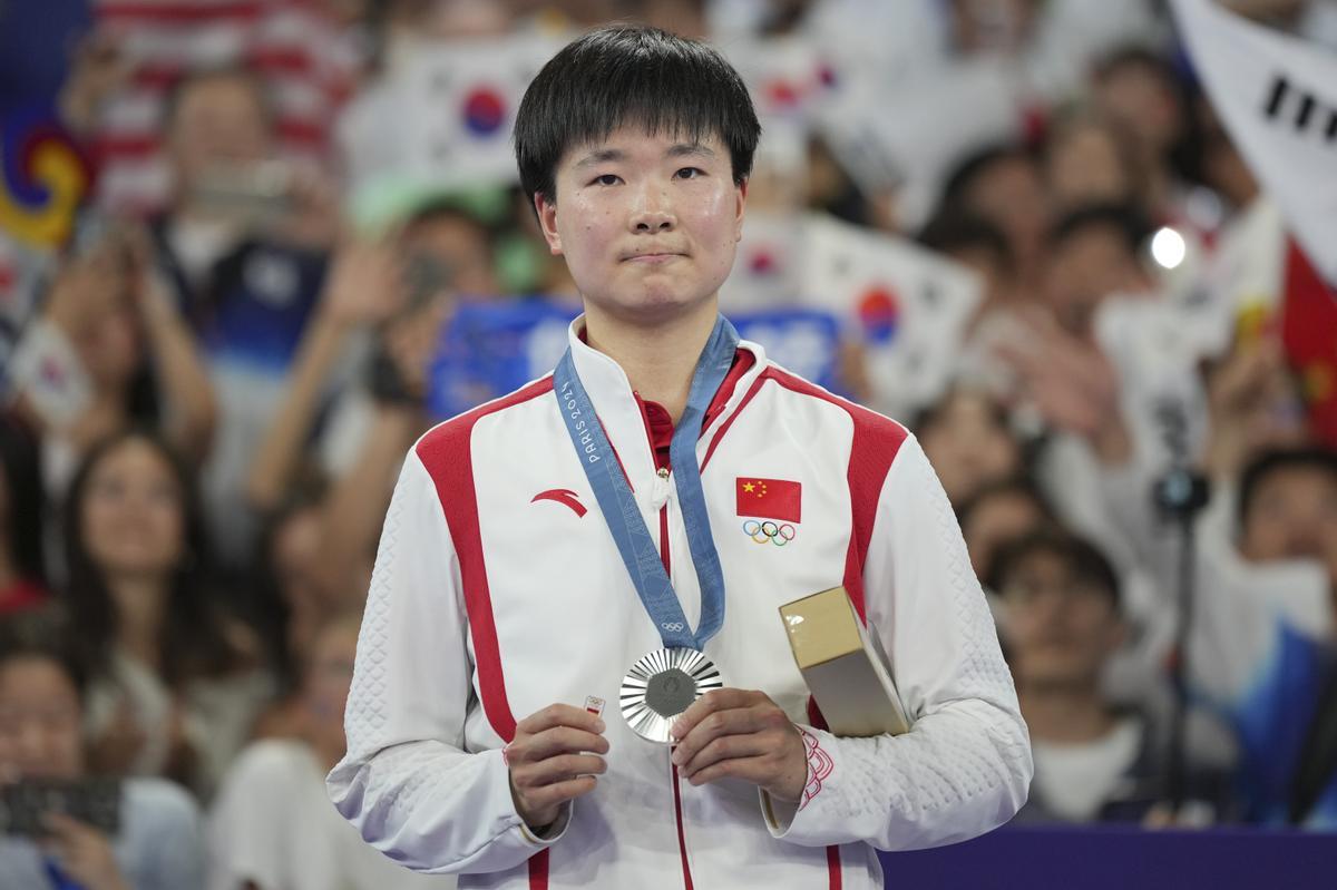 China's He Bingjiao celebrates on the podium after wining the silver medal at the badminton women singles at the 2024 Summer Olympics, Monday, Aug. 5, 2024, in Paris, France. (AP Photo/Kin Cheung)