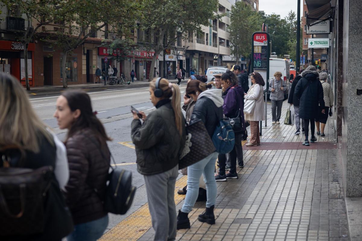 Una larga fila de personas esperando al autobús en una parada en Zaragoza