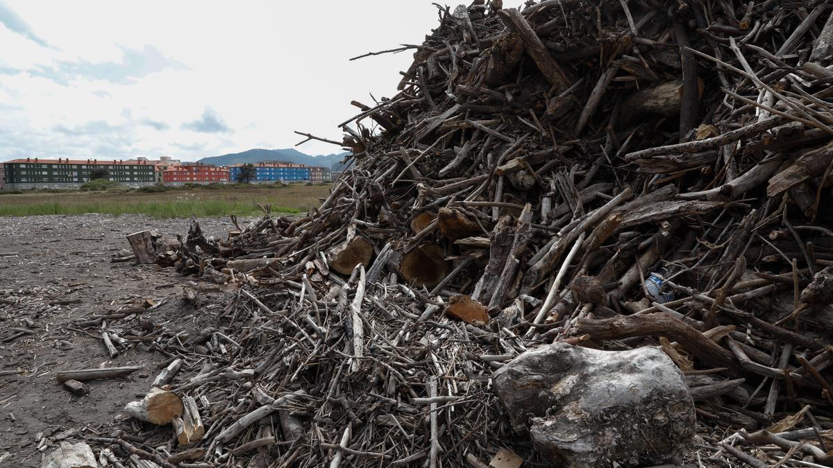 Madera apilada tras la limpieza en la playa de Los Quebrantos, en San Juan de la Arena.