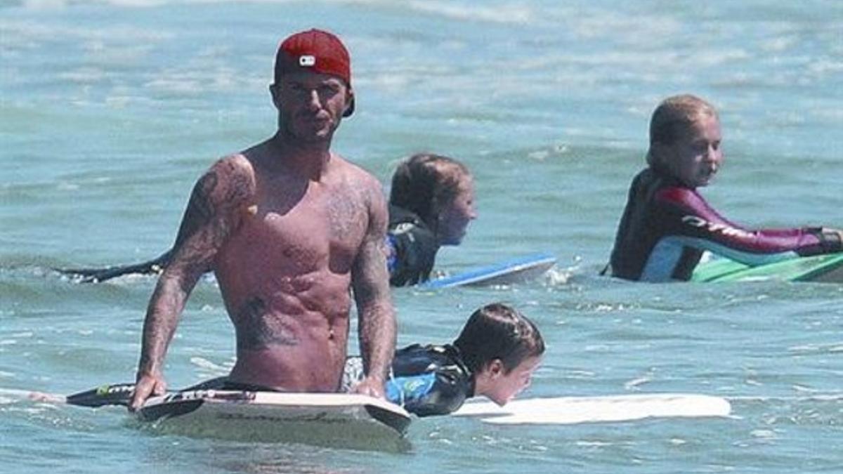 Beckham, con tabla de surf y gorra_MEDIA_1