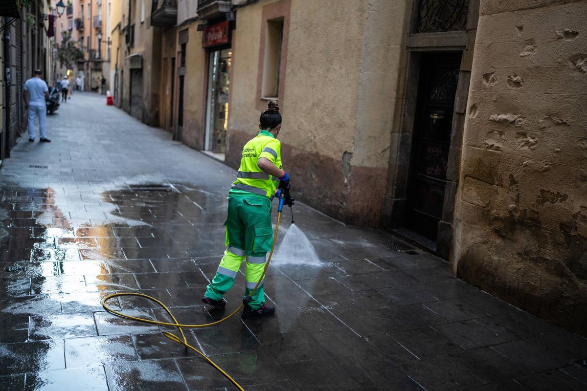 Barcelona. Jeffrey, propietario del bar Never, en la calle Cera 17 del barrio del Raval, retira con un carro de la compra las bolsas de basura acumuladas frente a su establecimiento antes de abrir el local, una situación que denuncia como habitual cada tarde. 29 de julio de 2026. Sociedad. AUTOR: ZOWY VOETEN