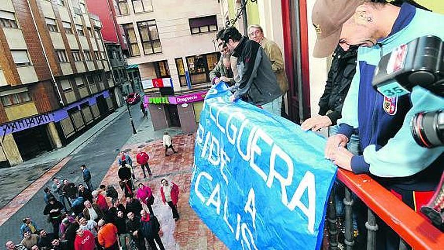 Empleados de Felguera Construcciones Mecánicas cuelgan una pancarta en el balcón del Ayuntamiento.