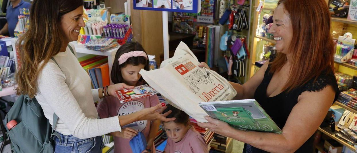 Una familia recoge sus libros de texto en la librería Cativos.