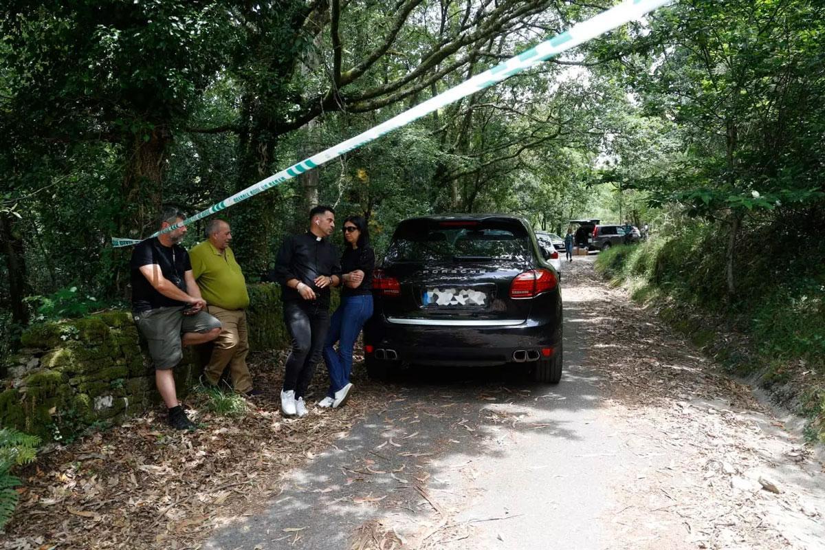 El alcalde de Campo Lameiro, Carlos Costa -de verde-, y el párroco, Fermín Santiago, en el lugar donde hallaron el cadáver y el coche calcinados.