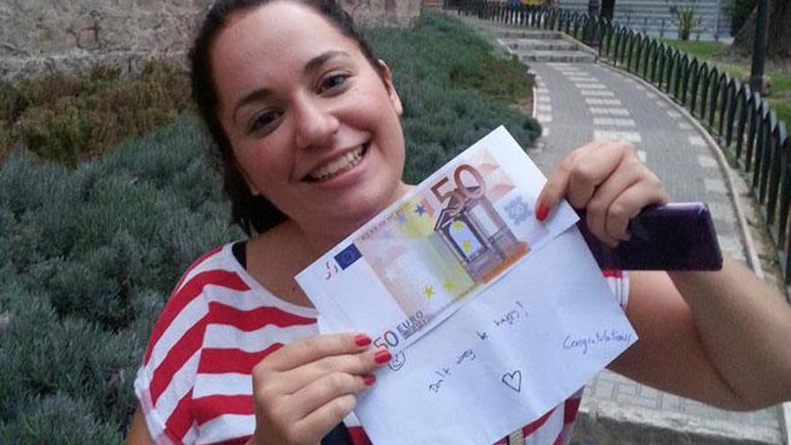 Una joven muestra uno de los billetes &#039;falsos&#039; repartidos por Málaga.