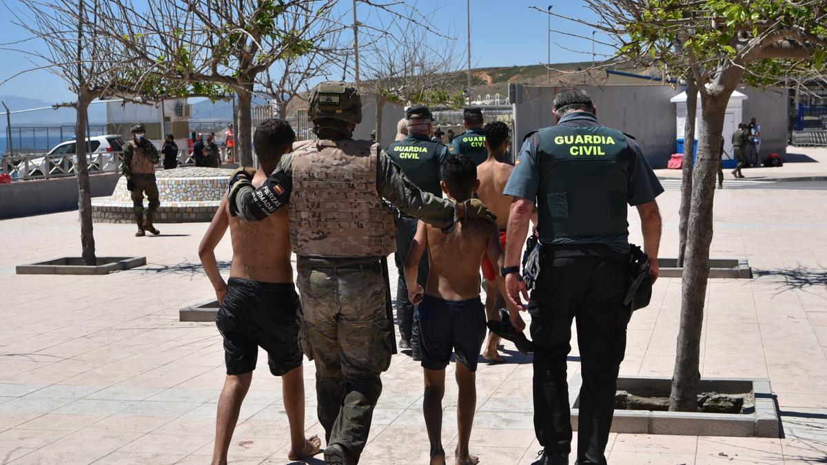 Un militar y un guardia civil ayudan a dos menores en Ceuta.