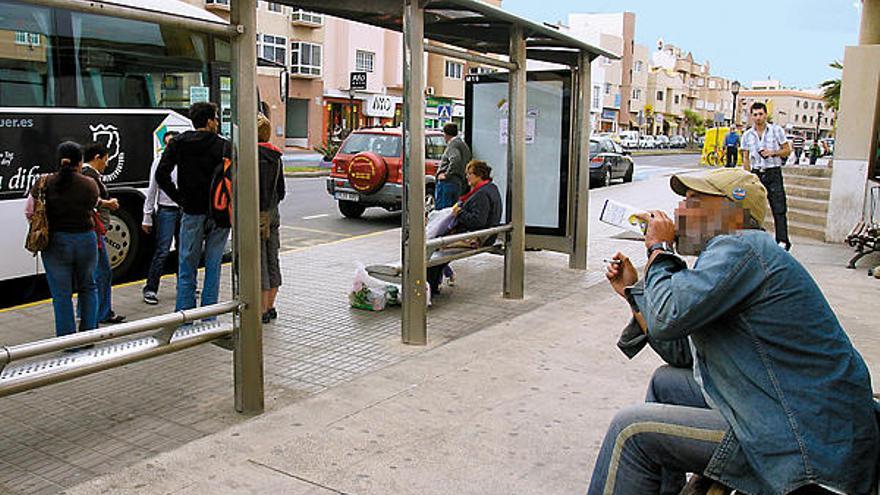 Una persona bebe vino en un envase de tetrabrik, en la parada de guaguas de Corralejo.