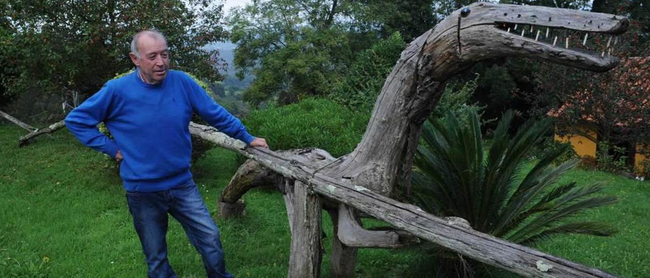 Emilio Llera, junto al dinosaurio de madera instalado en su jardín.