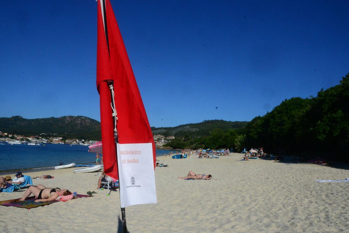 La playa de Arneles, este miércoles por la tarde, con la bandera roja que prohíbe el baño debido a vertidos fecales.