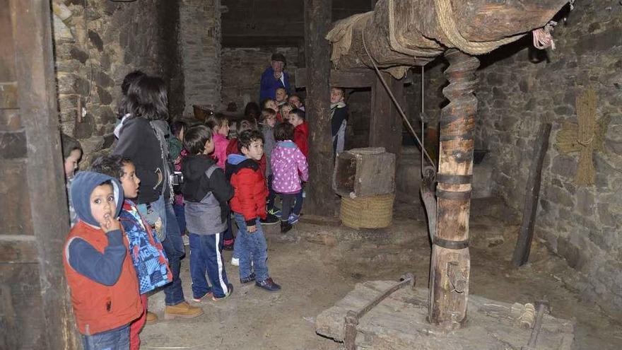 Un grupo de niños visita el antiguo lagar y, a la derecha, en la centrifugadora de la miel