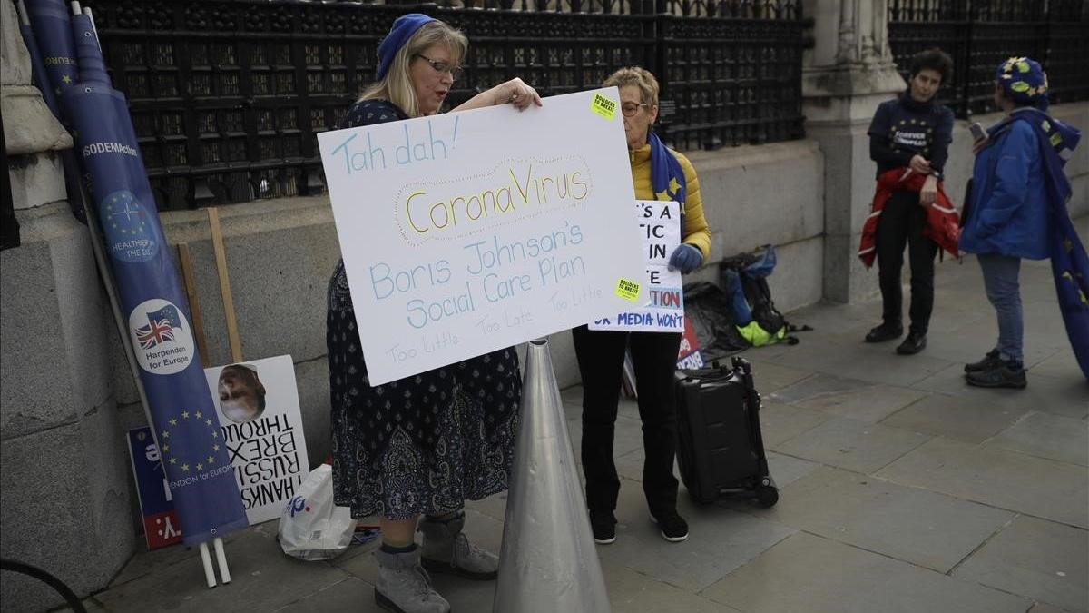 Detractoras del 'brexit' exhiben ante el Parlamento británico pancartas relacionándolo con la estrategia de Boris Johnson para combatir el coronavirus.